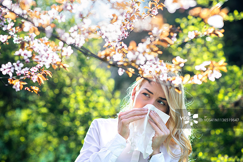 在鲜花盛开的花园里打喷嚏的女人图片素材
