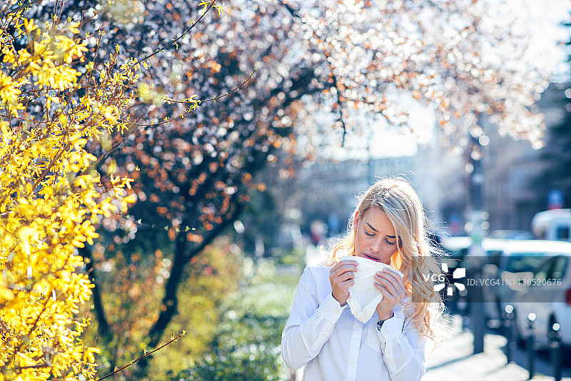 在鲜花盛开的花园里打喷嚏的女人图片素材