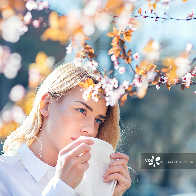 在鲜花盛开的花园里打喷嚏的女人图片素材