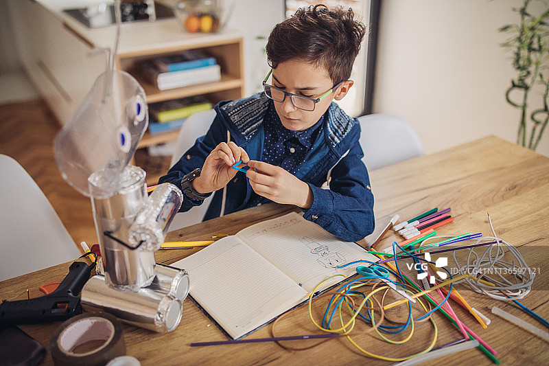 男孩为学校科学项目组装机器人图片素材