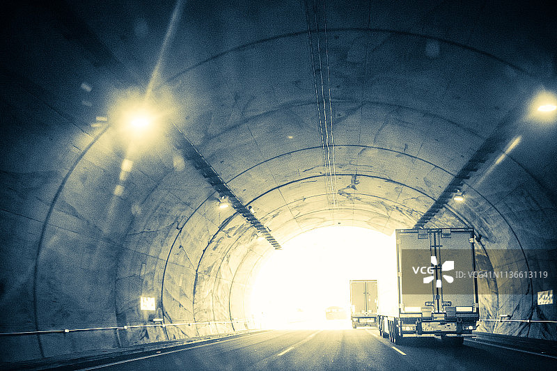 隧道尽头的光芒，隧道内卡车和汽车的交通，复古风格图像图片素材