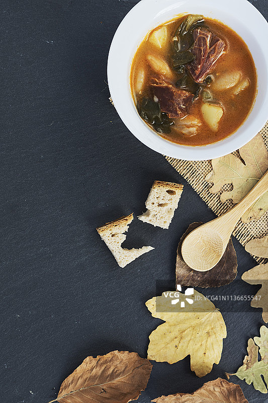 阿斯图里亚斯豆炖肉、木勺、干燥的秋叶和面包片图片素材