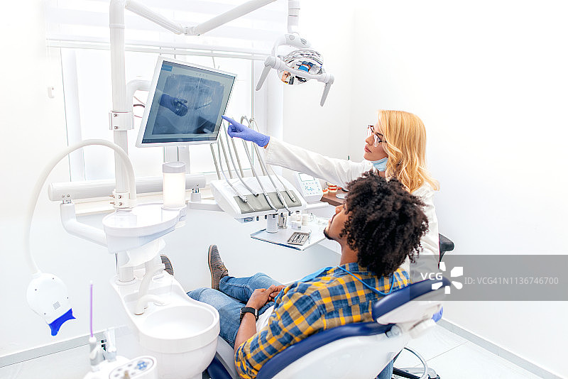 牙医向男患者讲解牙齿X光片图片素材