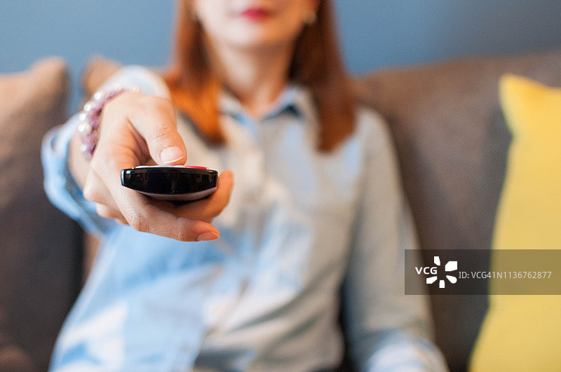 年轻女子拿着电视遥控器图片素材