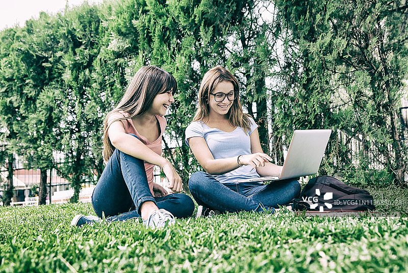 教育概念：快乐的学生朋友在户外草地上用笔记本电脑学习图片素材