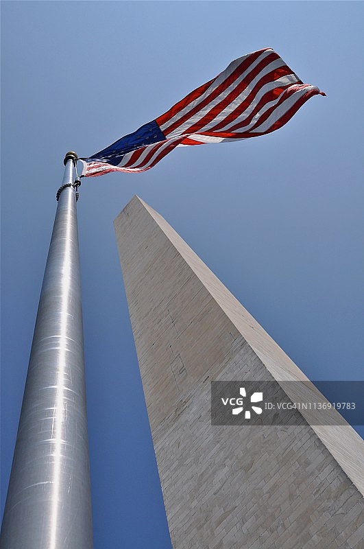 蓝天下华盛顿纪念碑和美国国旗的仰视景观图片素材