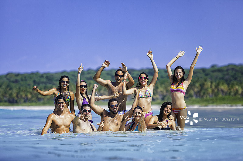 一群年轻人在热带绿松石海滩的波浪中嬉戏的春假图像图片素材