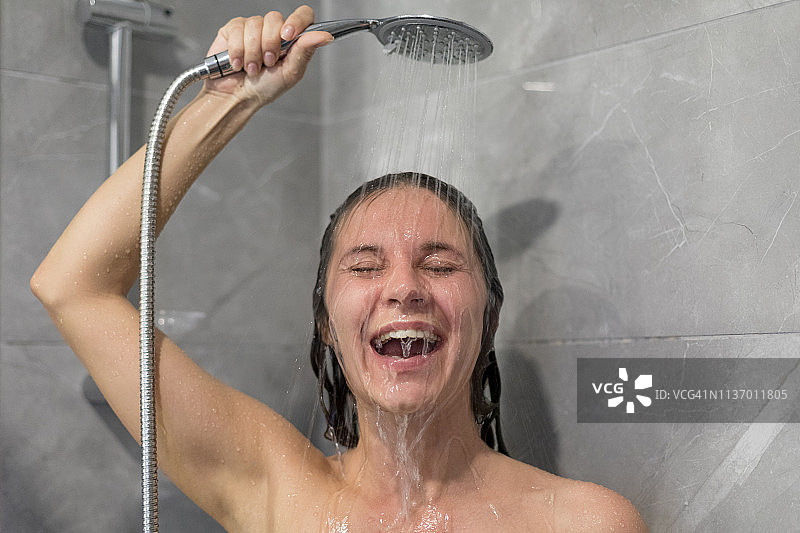 在淋浴时欢笑的年轻女人图片素材