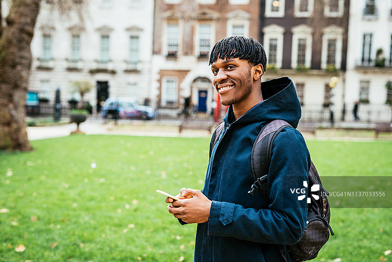 在伦敦使用智能手机与朋友交流的黑人男士图片素材