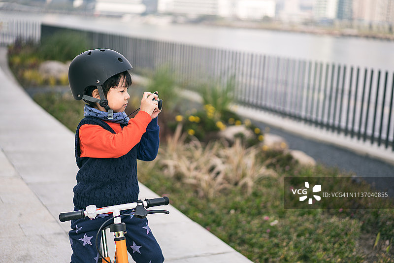 戴着运动头盔玩相机的小男孩肖像图片素材