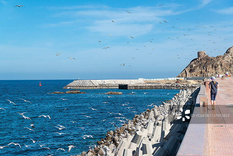 在阿曼马斯喀特海岸线长廊上行走的女孩图片素材