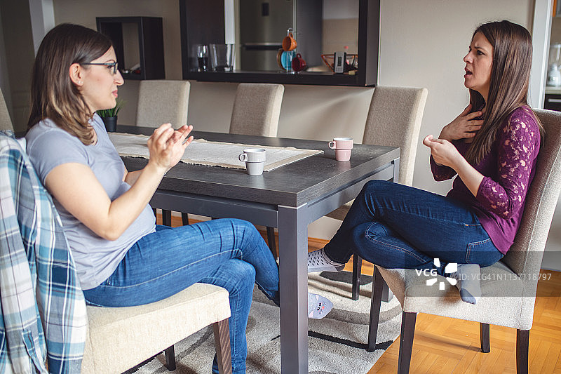 年轻女性用手语交谈时喝咖啡图片素材