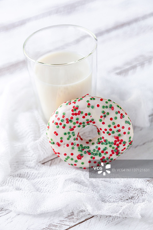 白色背景上的带白色糖霜、砂糖颗粒和一杯牛奶的甜甜圈图片素材