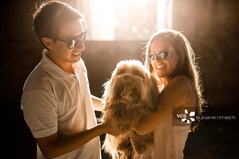 情侣和他们的狗在室内，逆光图片素材