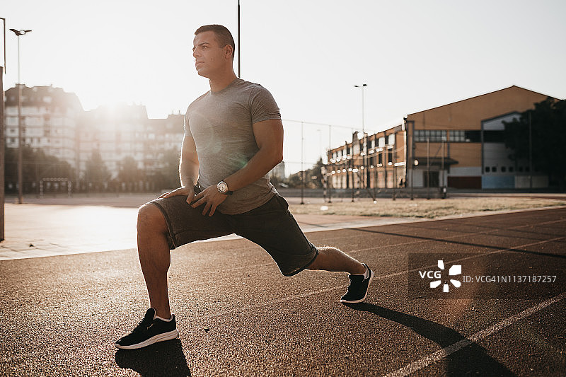 年轻男人在跑道上伸展运动图片素材