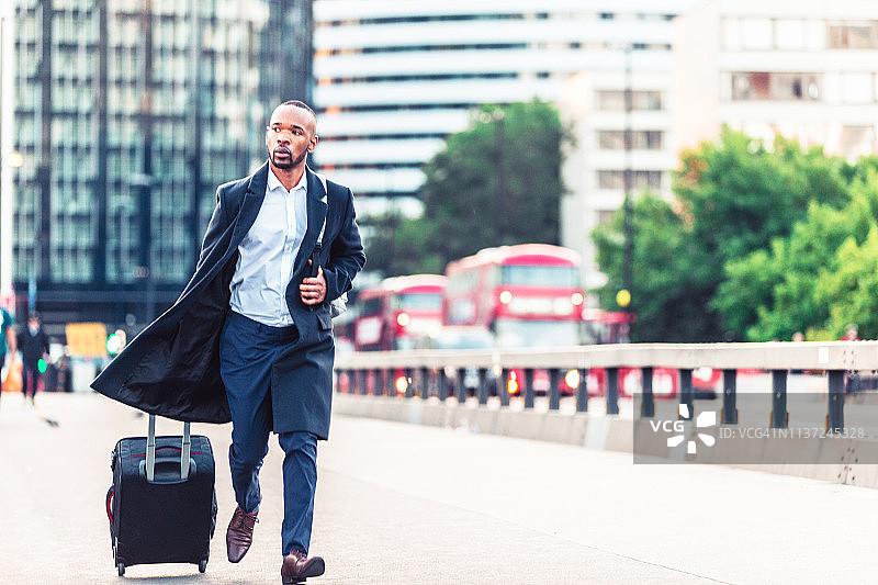 商人拖着行李箱在伦敦威斯敏斯特桥上赶路图片素材