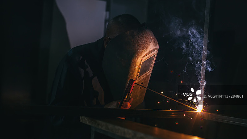 戴防护面罩焊接金属的工人图片素材