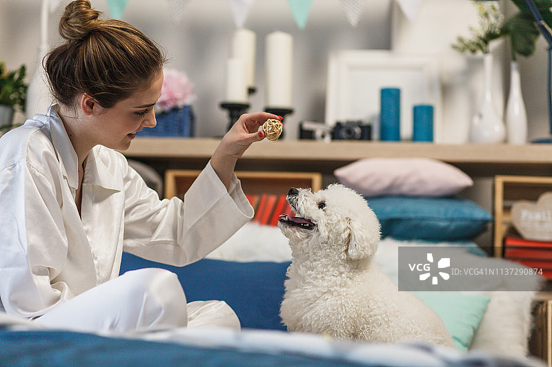 女人和狗一起坐在床上玩耍图片素材