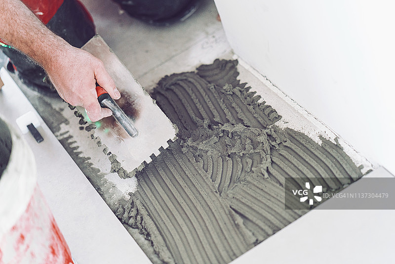 瓦工在地面上涂抹粘合剂图片素材