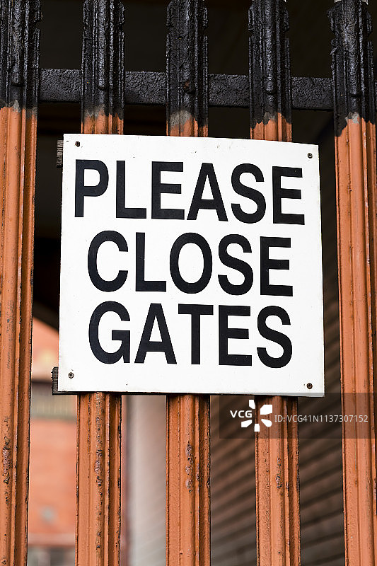 旧橙色金属门上的“请关闭大门”标志图片素材
