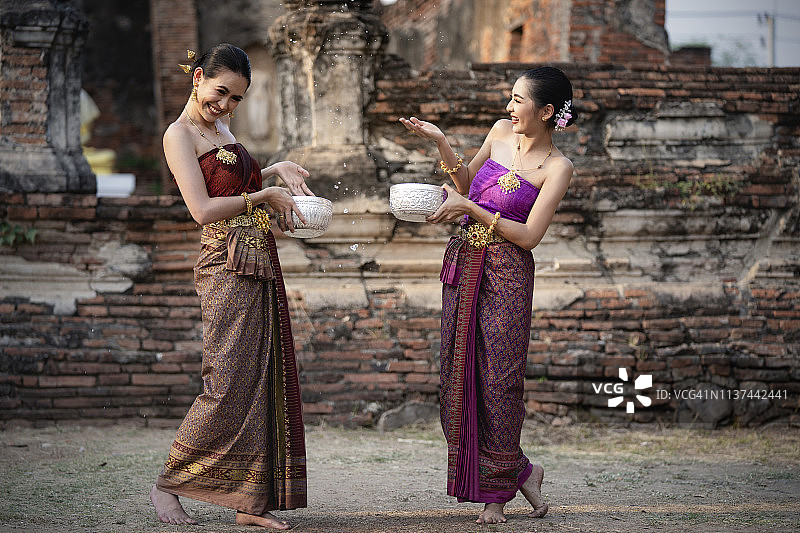 泰国泼水节：快乐的泰国女孩穿着泰国传统服饰在泼水节期间泼水图片素材