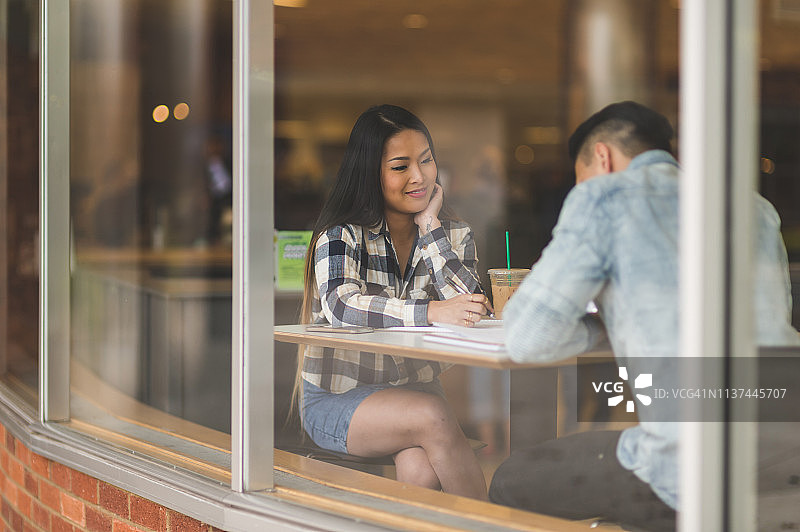 年轻亚洲情侣在咖啡馆学习图片素材