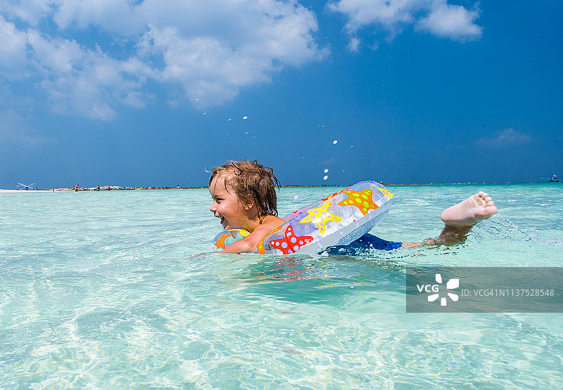 快乐小男孩在海中游泳圈玩耍图片素材