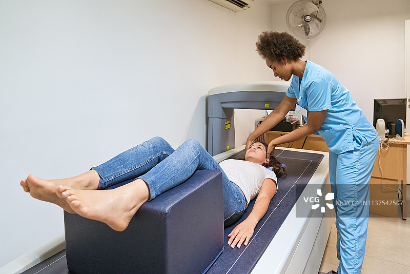 年轻的护士为妇女准备骨密度扫描图片素材