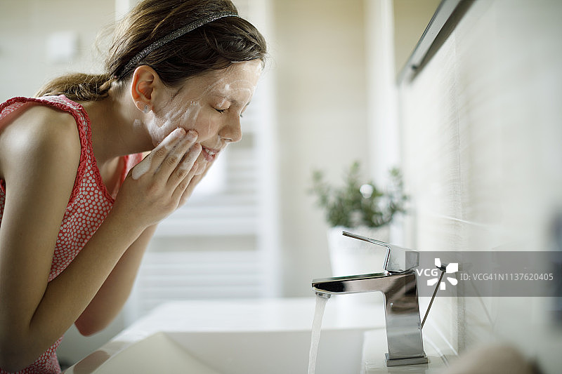 在浴室用清洁剂清洁面部的少女图片素材