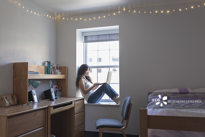 在宿舍里使用笔记本电脑的年轻女大学生图片素材