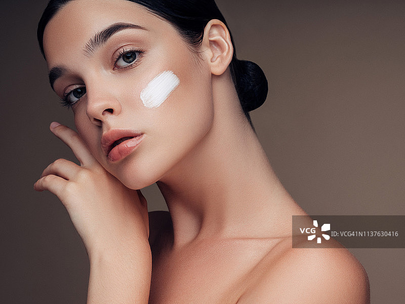 美丽年轻的女人涂抹护肤霜图片素材