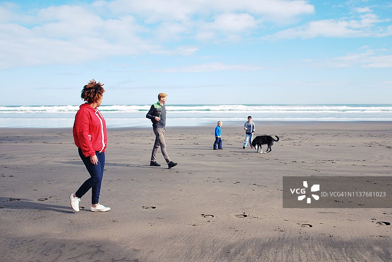 一家人和朋友在冬天于海滩遛狗图片素材