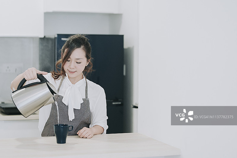 中国女性在厨房倒热水冲咖啡图片素材