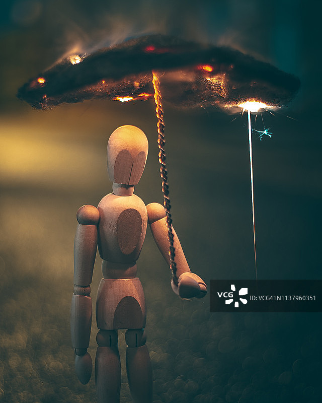 木制人体模型拿着燃烧的钢丝棉伞图片素材