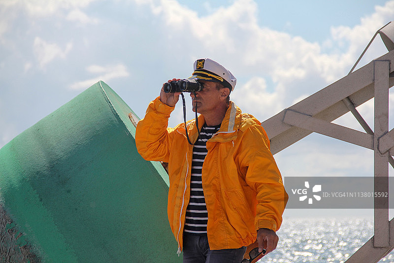 正在用双筒望远镜观察的船长图片素材