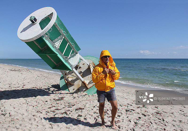 男子站在海滩上，靠近一个废弃的大型航道标志图片素材