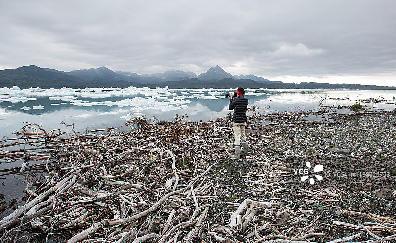 独自在水边拍摄冰山的女人摄影师图片素材