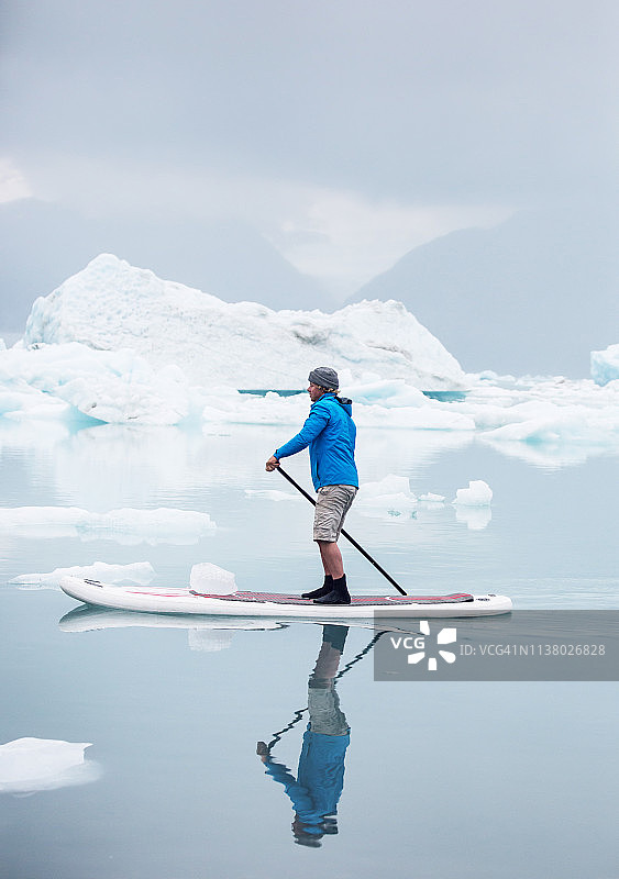 男子在阿拉斯加冰川泻湖上划桨图片素材