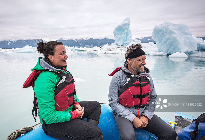 男女乘坐木筏在冰川泻湖上图片素材