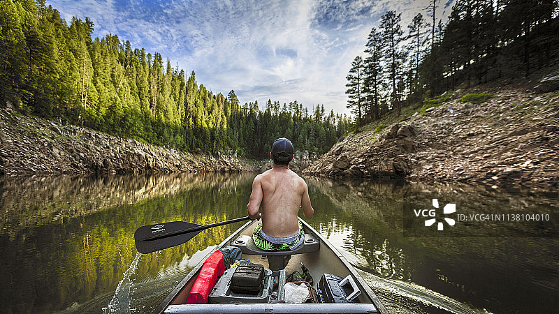 从独木舟向下看，男人在平静的水面划桨图片素材