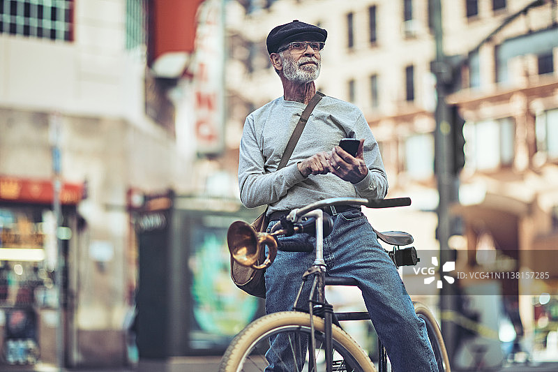 年长男人在城市骑行时使用智能手机图片素材