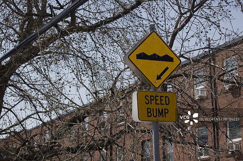 树木和建筑物前的减速带标志图片素材