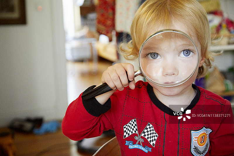 用放大镜观察的蓝眼睛小男孩图片素材
