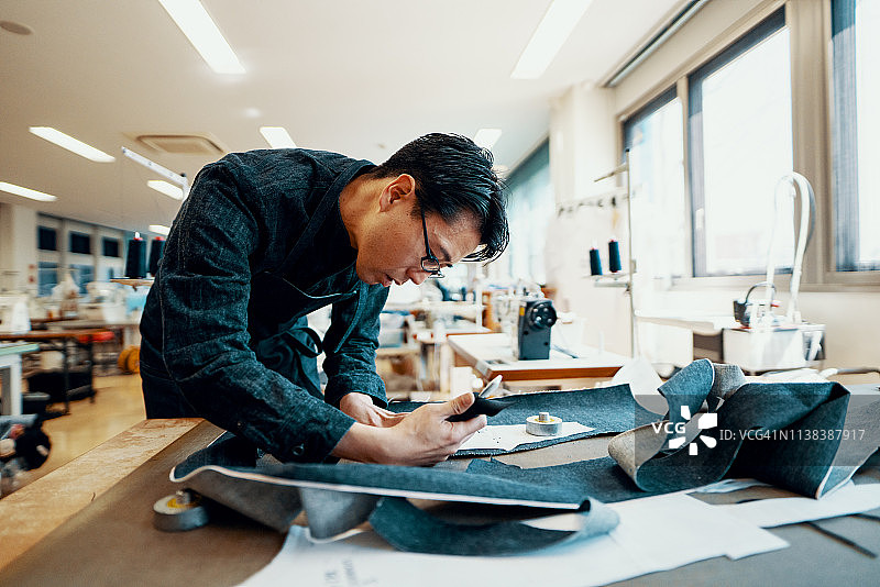 中年裁缝在他的设计工作室制作牛仔产品图片素材