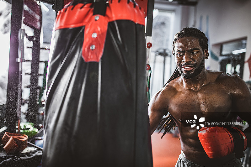在健身房里打拳击沙袋的非裔美国健壮男子图片素材