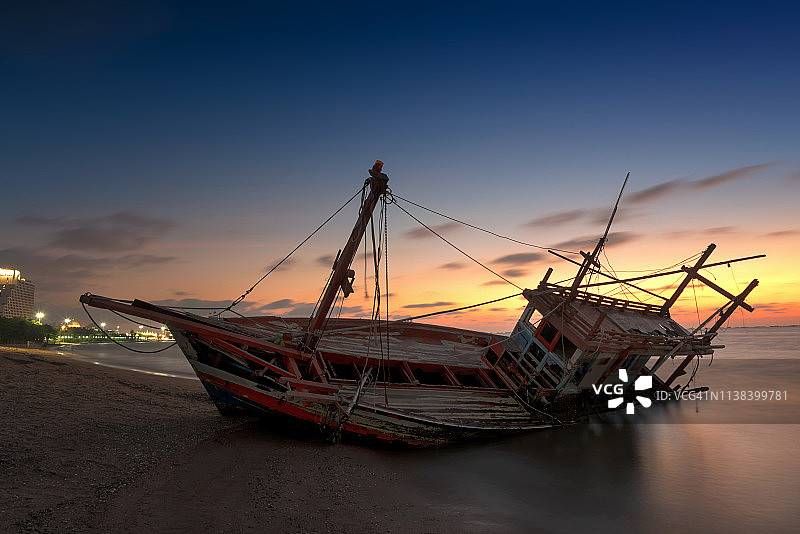 暮色时分海滩上的废弃木制渔船残骸图片素材