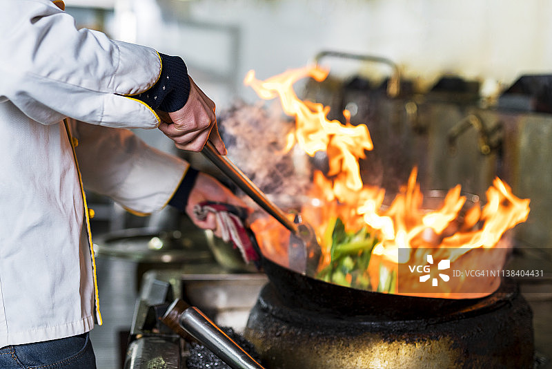 厨师在厨房炉灶的煎锅中用火焰烹饪图片素材
