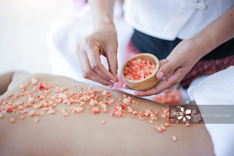 年轻女子在水疗沙龙接受盐浴按摩图片素材