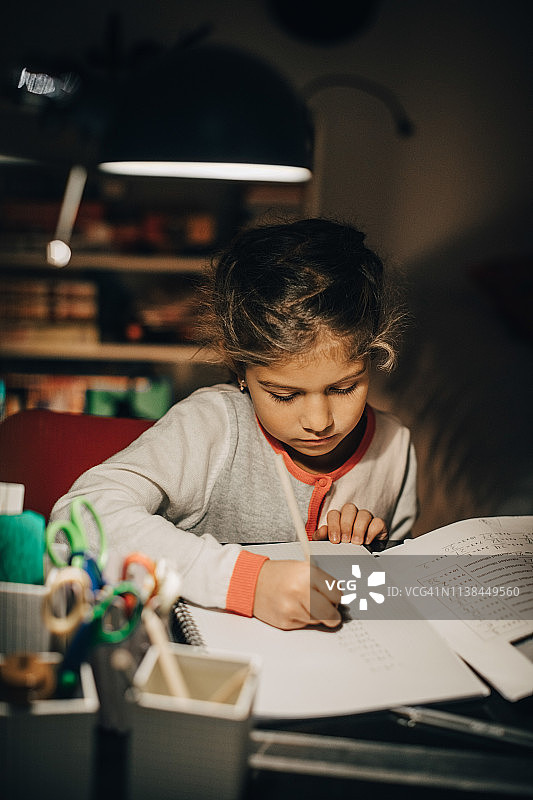 高角度拍摄在家中坐在书桌旁写作业的女孩图片素材