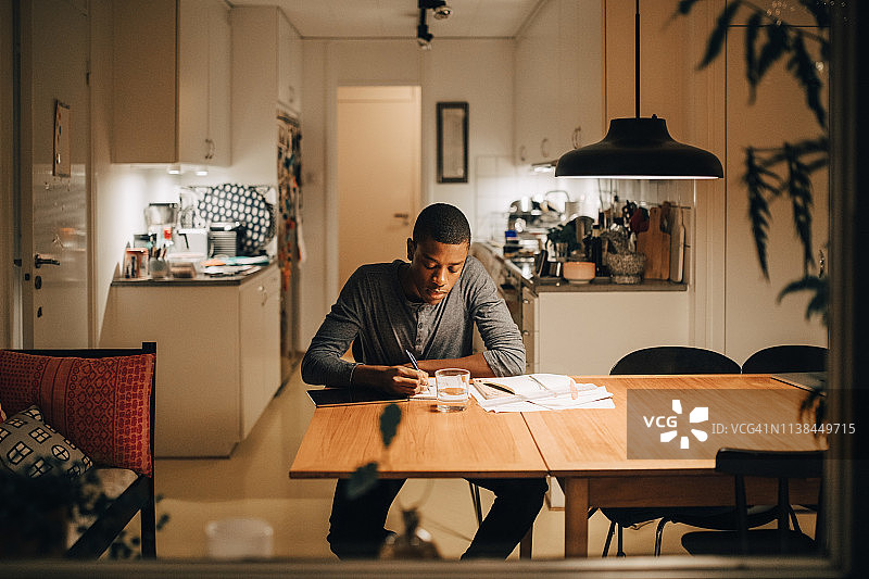 透过窗户看男孩在家写作业图片素材